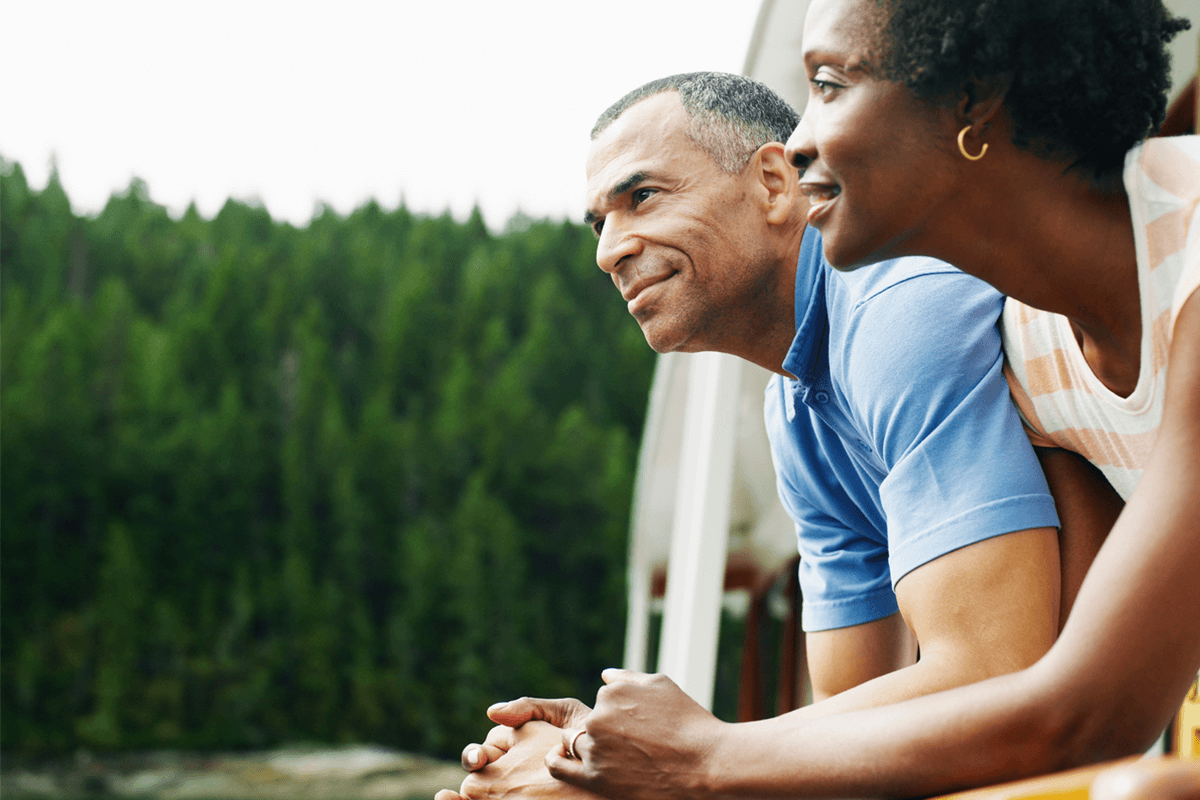 Couple standing next to each other outside. Trees in background